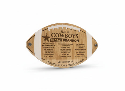 Wooden plaque shaped like a football with engraved text on a wooden background