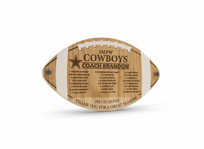 Wooden plaque shaped like a football with engraved text on a wooden background