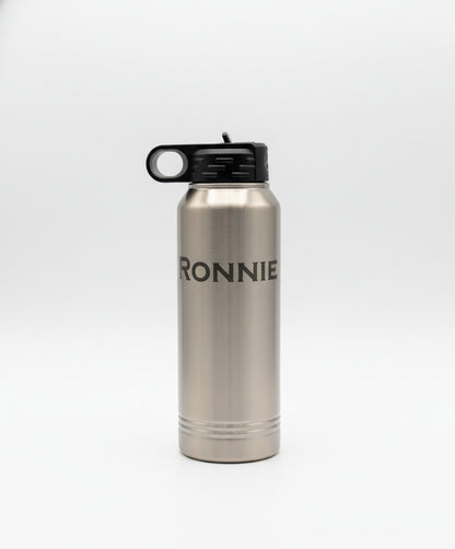 Silver water bottle with 'RONNIE' branding on a wooden surface with a plant in the background.